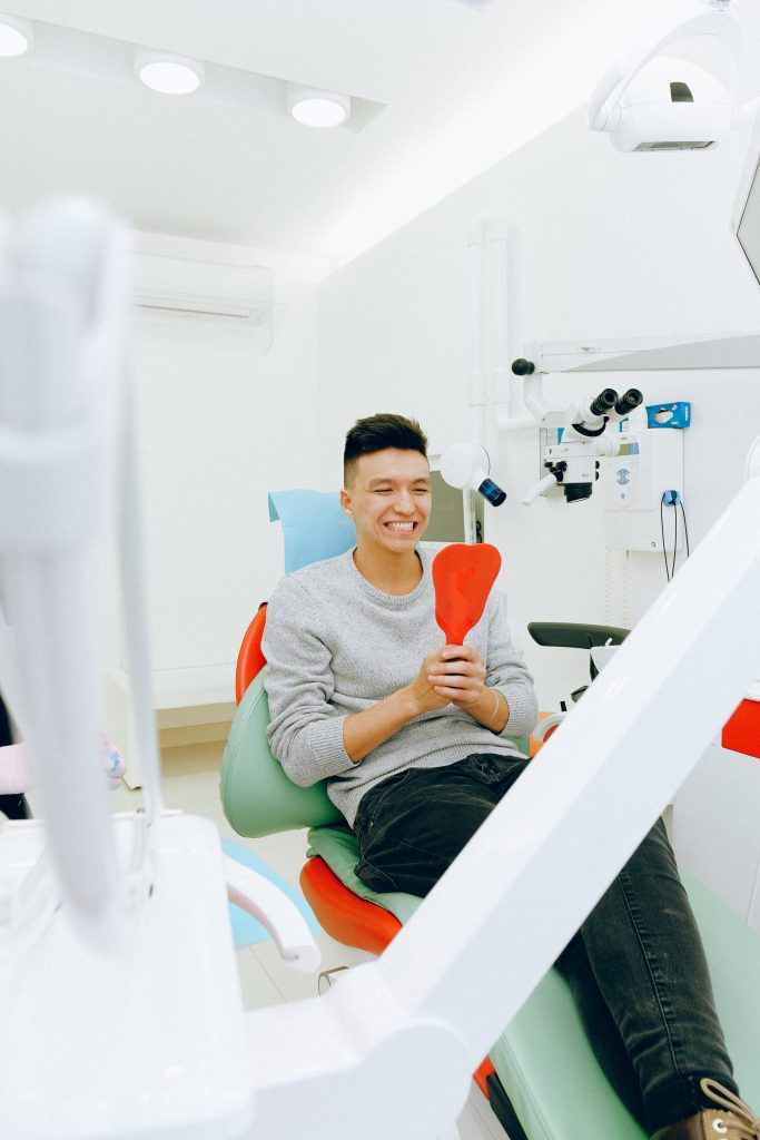 guy smiling into a mirror while in the dentist chair