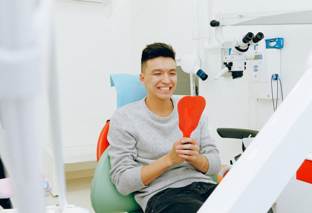 guy smiling into a mirror while in the dentist chair